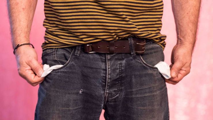 Мужчина выворачивает пустые карманы своих джинсов – пора подавать заявку на неплатежеспособность
