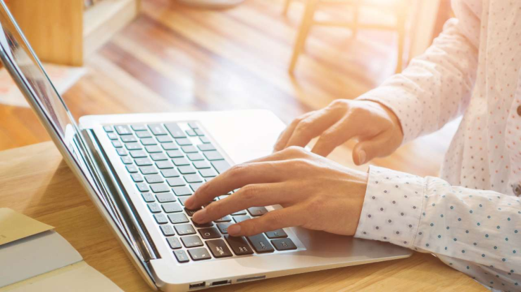Крупным планом руки на клавиатуре ноутбука, стоящего на столе, для оформления новых кредитов онлайн