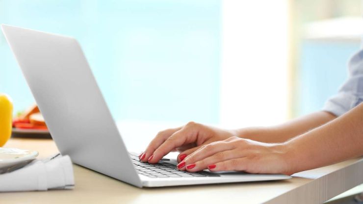 Sieviete ar sarkani nolakotiem nagiem datorā darbojas pie sava jauna partnermārketinga projekta