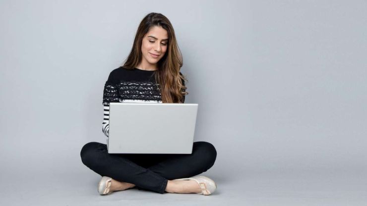 Sieviete, sēžot uz grīdas, meklē datora populārākos aizdevumus