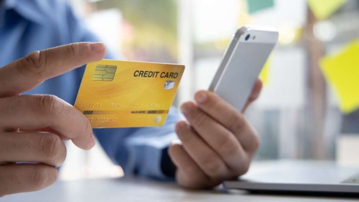 Мужчина через телефон оформил кредитную линию и держит в руке кредитную карту, на которой взятые деньги