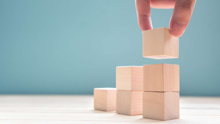 Рука строит башню из деревянных кубиков, как концепция психологии успеха