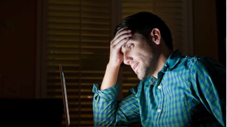 Vīrietis rūtainā kreklā skatās datora ekrānā un saprot, ka bez oficiāliem ienākumiem nevarēs saņemt kredītus bez darba vietas