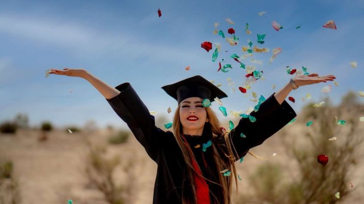 Jauniete ar aizvērtām acīm absolventu apģērbā un cepurē met gaisā konfetti , jo ir pabeigusi augstskolu, pateicoties studiju kredītam