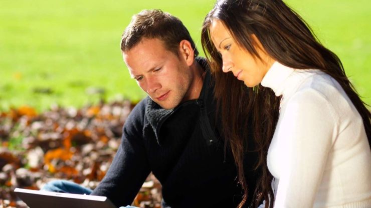Пара сидит в парке и просматривает в ноутбуке варианты кредитов до 5000 евро