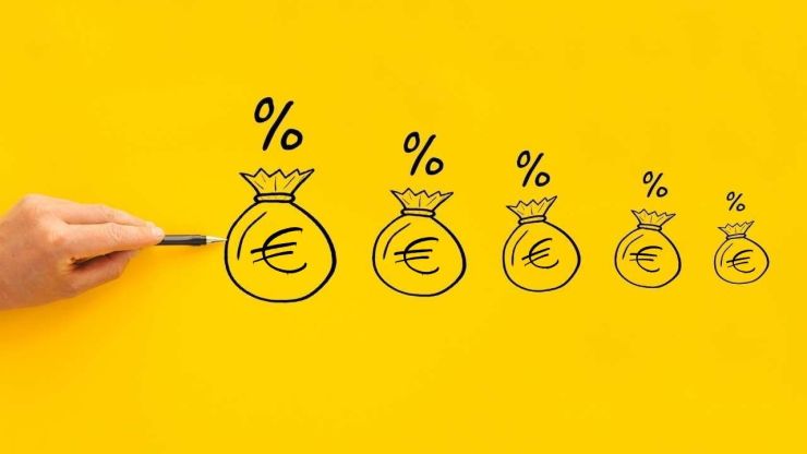 Persona ar pildspalvu rāda uz lētākiem aizdevumiem – naudas maisiņiem virs kuriem ir % zīme