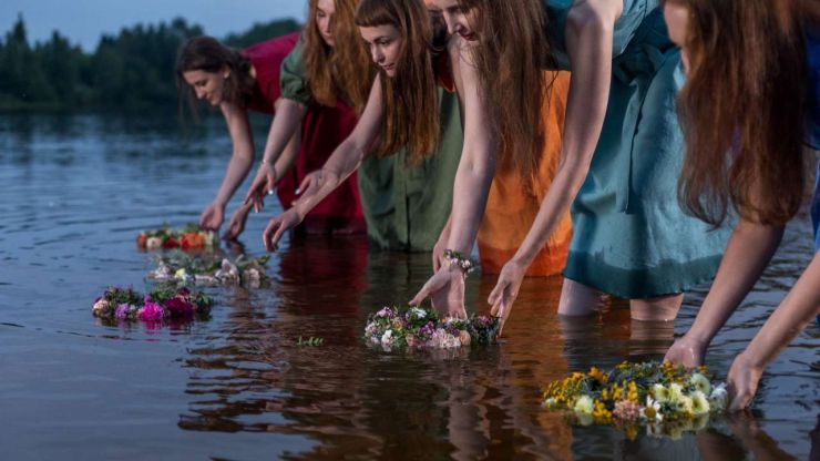 Piecas jaunas sievietes laiž pa upi savus Līgo svētku vainagus, jo tā ir viena no latviešu tradīcijām