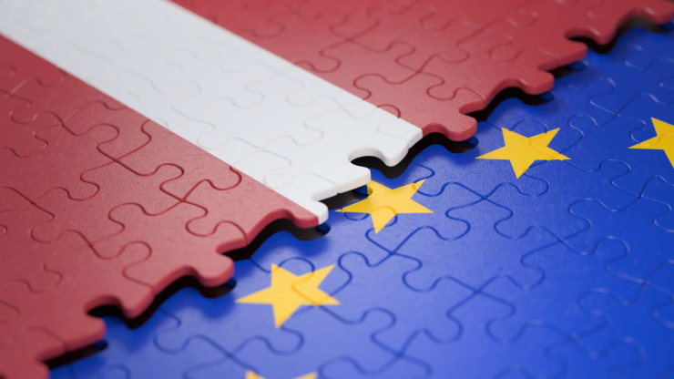 Частички сложенных пазлов в виде флагов Латвии и Евросоюза, у которых общие фиатные деньги – евро