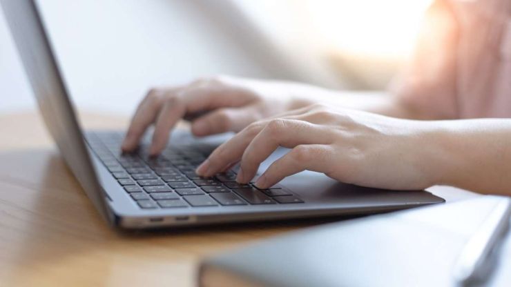 Девушка сидит за ноутбуком и ищет в интернете, где взять кредит, который поможет сэкономить деньги