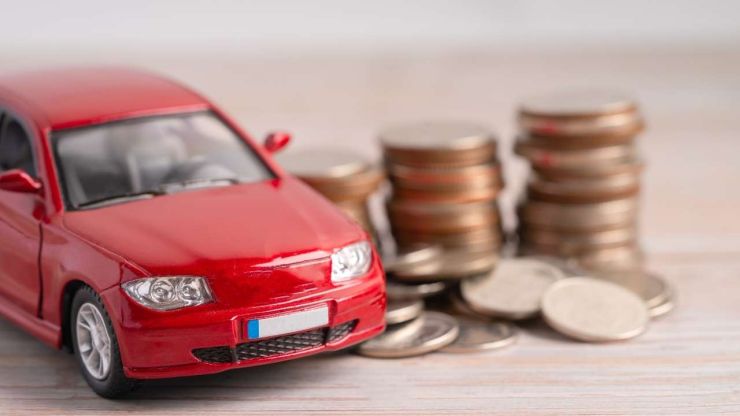 Sarkanā spēļu mašīna ar monētām fonā simbolizē kredītu pret auto ķīlu
