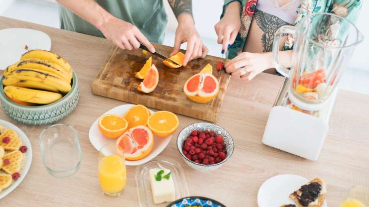 Пара нарезает грейпфрут и апельсины, потому что ведет здоровый образ жизни, который является частью хорошей финансовой привычки