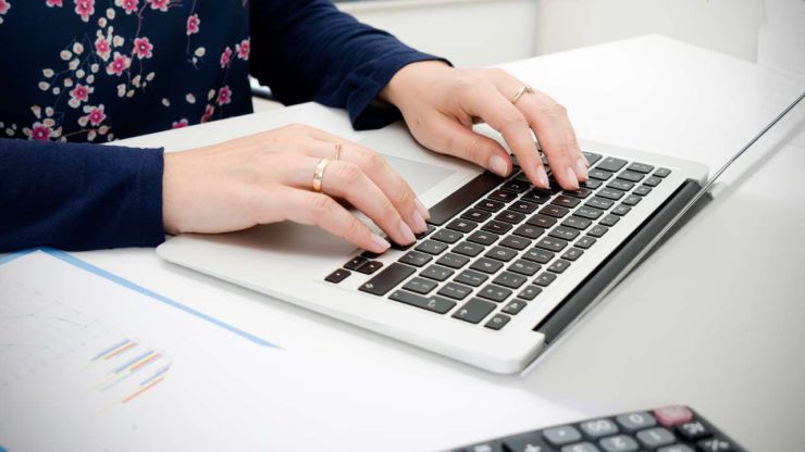 Женщина на ноутбуке заполняет годовую декларацию, чтобы вернуть налоги в Латвии