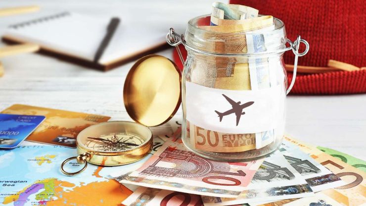 Uz galda karte, kompass, eiro banknotes un burciņa ar naudu, jo nepieciešams pareizi organizēt finanses priekš ceļojuma