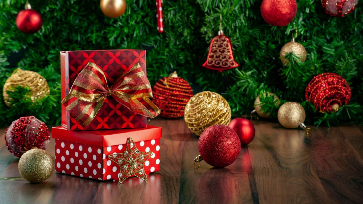 На полу у елки с игрушками стоят две коробки с подарками на Рождество