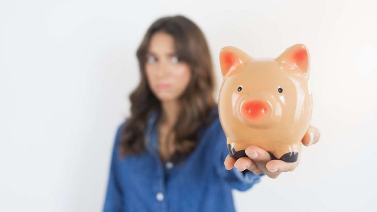 Женщина в состоянии стресса держит пустую свинку-копилку, потому что так на нее влияет психология денег
