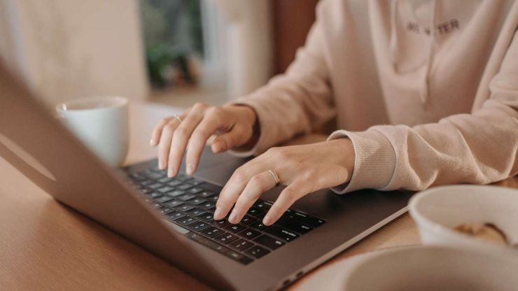 Sieviete pie rīta kafijas krūzes portatīvajā datorā meklē internetā nebanku aizdevumu priekšrocības