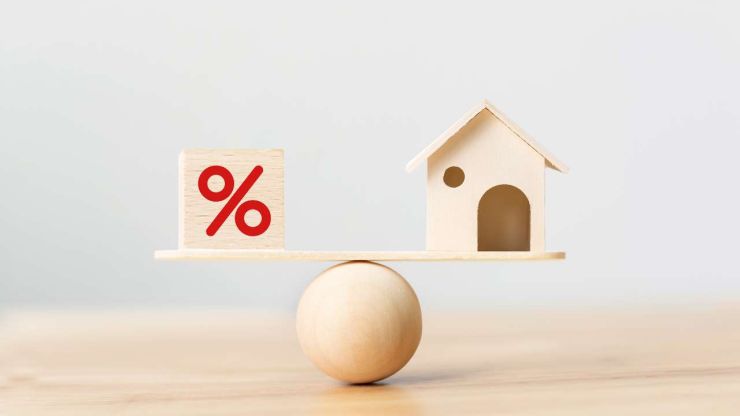 Самодельные деревяные весы с кубиком «%» и домиком, чтобы понять влияние инфляции на процентные ставки и Euribor