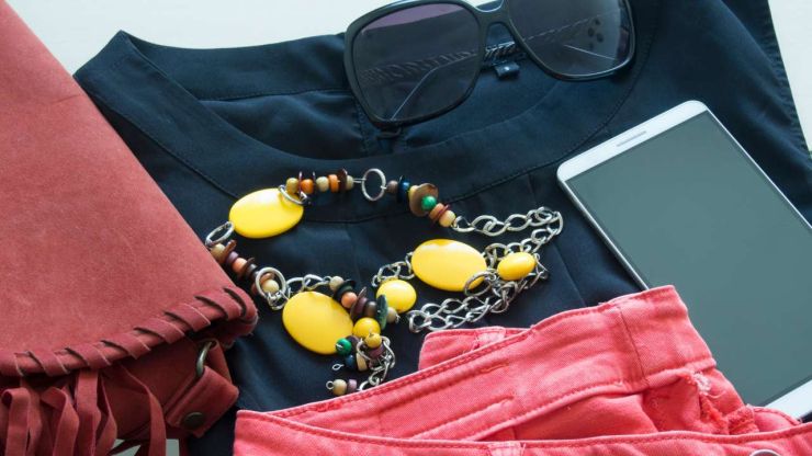 Обновленный гардероб из собранного образа – черная блузка, розовые джинсы, красная сумка, солнечные очки и желтые бусы