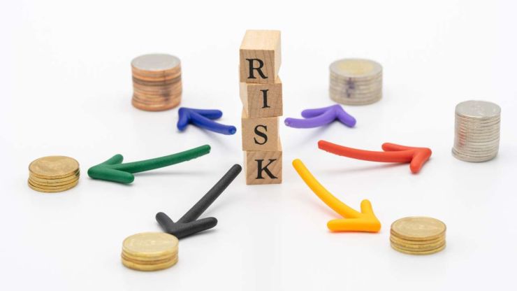 Vārds “risk” no koka klučiem un 6 dažādas monētu kaudzītes – svarīgs investēšanas pamatprincips ir diversifikācija