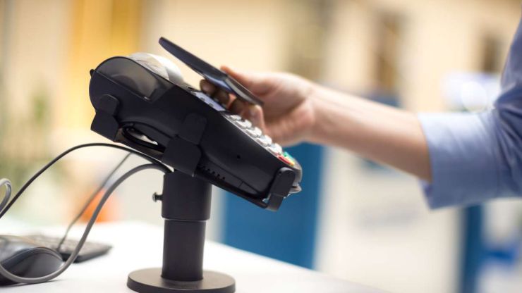 Человек оплачивает покупку при помощи своего смартфона, к которому привязана банковская карта с виртуальными деньгами