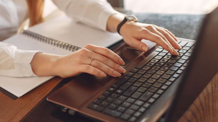 Sieviete sēž pie galda un portatīvajā datorā meklē informāciju, kā izvēlēties piemērotāko aizdevēju