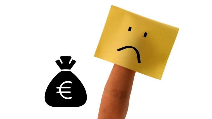 Attēlā redzama uz pirksta pielīmēta lapiņa ar bēdīgo smaidiņu un blakus stilizēts maisiņš ar eiro – ātrā kredīta ar parādsaistībām simbols