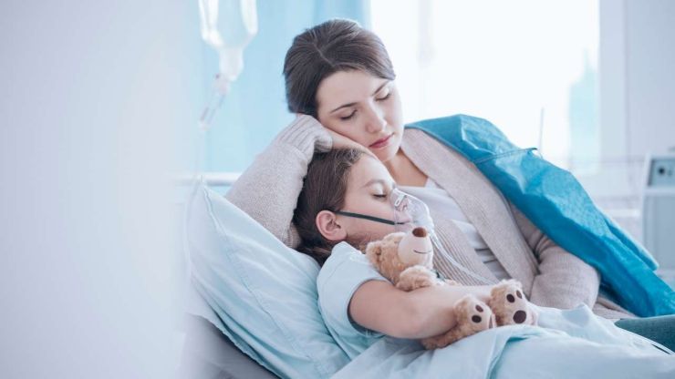 Мама обнимает дочку, лежа на больничной койке, т.к. ребенок серьезно заболел и пришлось брать больничный лист