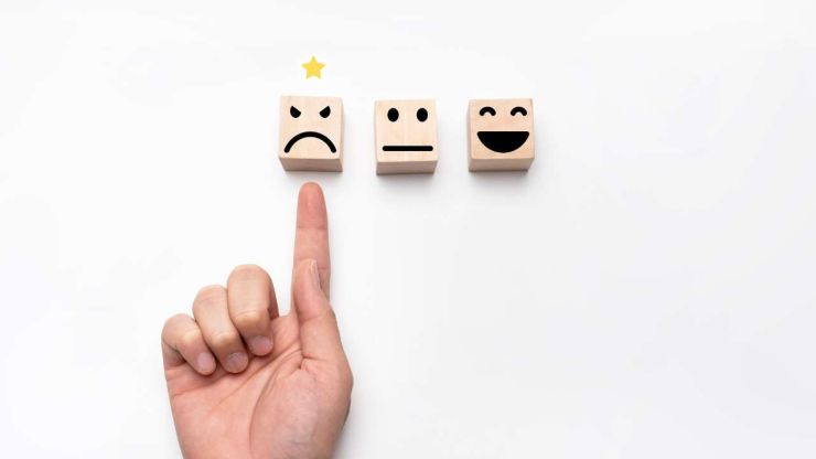 Три кубика с разными эмоциями, и палец указывает на злость – эмоцию, которая влияет на финансовые решения