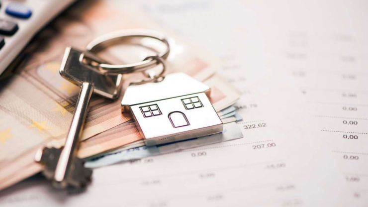 На столе лежат деньги и ключ с брелком в виде домика – покупка жилья является положительным ответом в вопросе «стоит ли брать кредит»