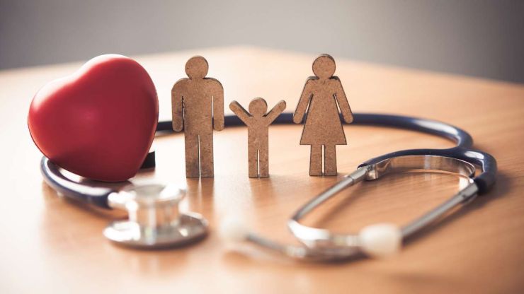 На столе экспозиция из стетоскопа, сердца и родителей с ребенком – страховой полис от несчастных случаев