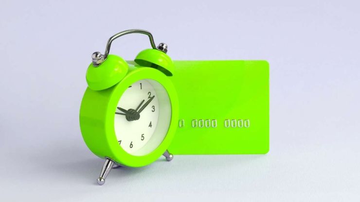 Klusā daba ar zaļo pulksteni un zaļo kredītkarti, kurā ir summa, kas noformēta kā īstermiņa kredīts