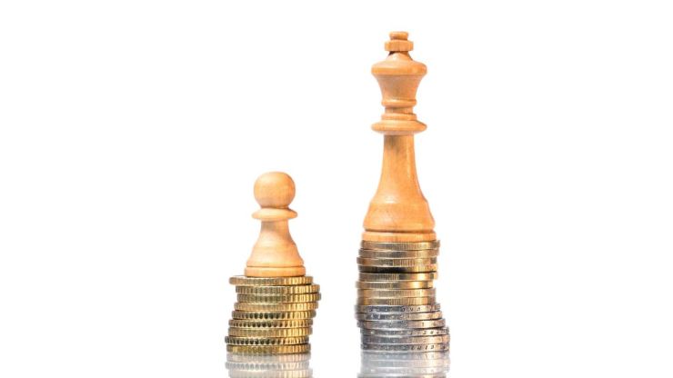 Пешка и Ферзь стоят на меленькой и высокой пирамиде из монет – процентная ставка по кредиту зависит от финансового положения