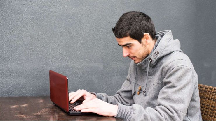 Vīrietis savā datorā meklē kreditorus, kas piedāvā pirmo kredītu bez maksas