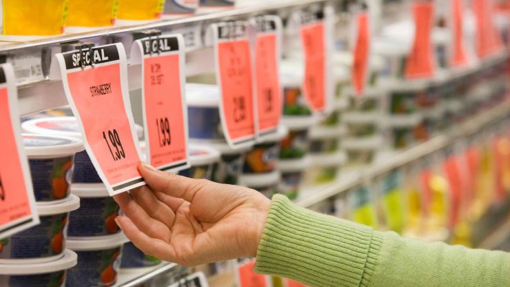 Женщина в магазине просматривает цены продуктов на полках, поскольку ее интересует вопрос ценообразования