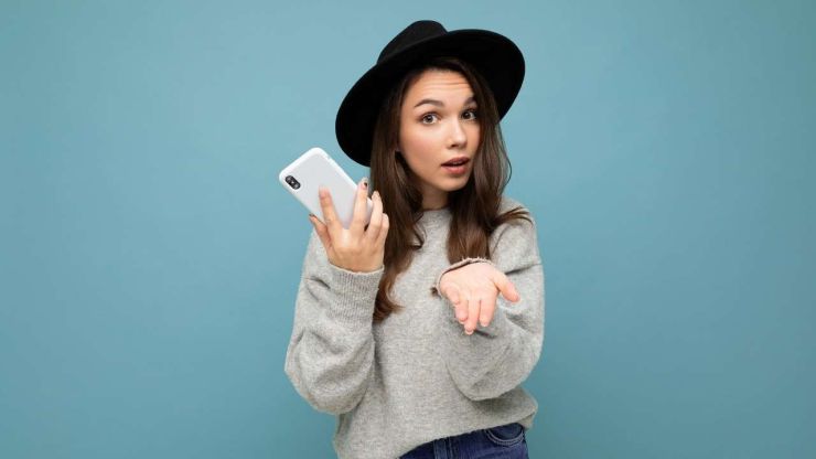 Девушка в шляпке с телефоном в руках протягивает вторую руку, чтобы получить кредит без официальной работы