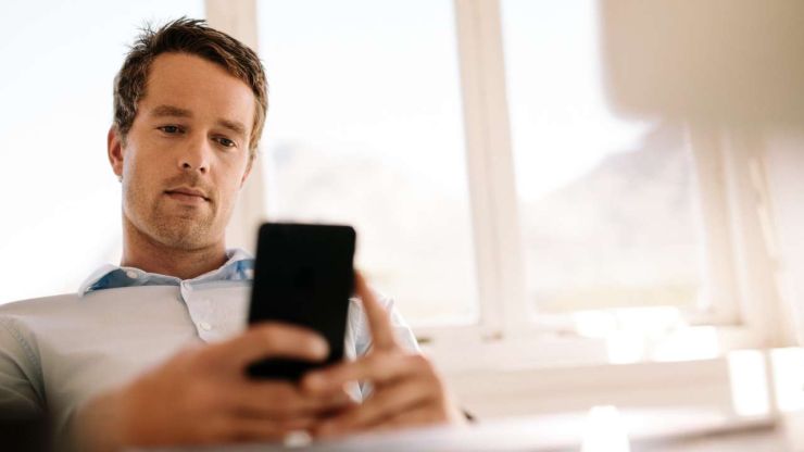 Vīrietis izmanto lejupielādēto mobilo aplikāciju, kas ir ērts digitālais risinājums finanšu pārvaldīšanai