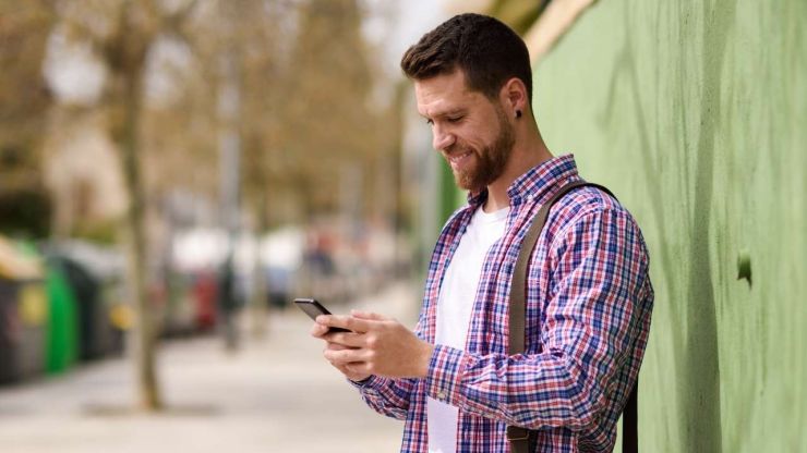 Мужчина улыбается, читая в телефоне подтверждение на беспроцентный кредит