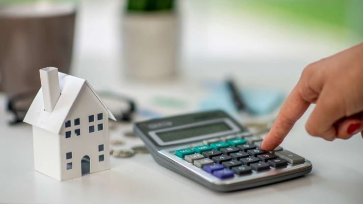 Женщина на калькуляторе считает возможные расходы за весь период выплаты ипотечного кредита