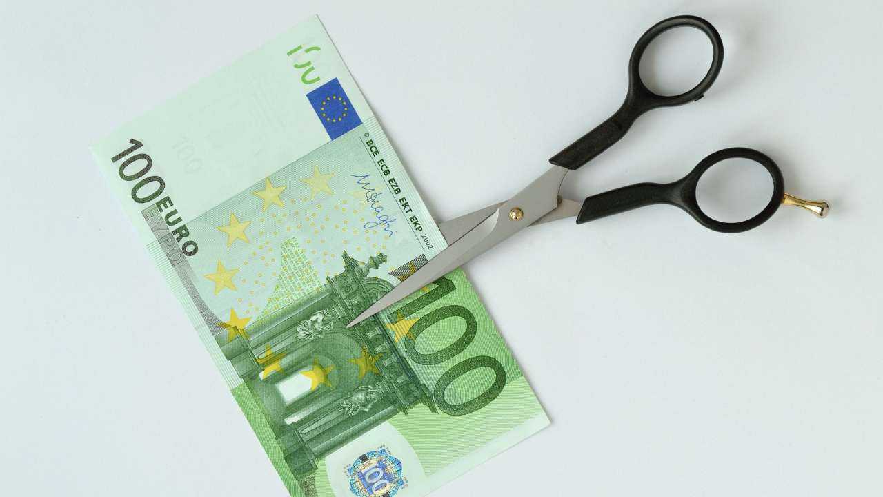 Купюру в 100 евро перерезают на пополам ножницы, потому что необходимо сокращать повседневные расходы
