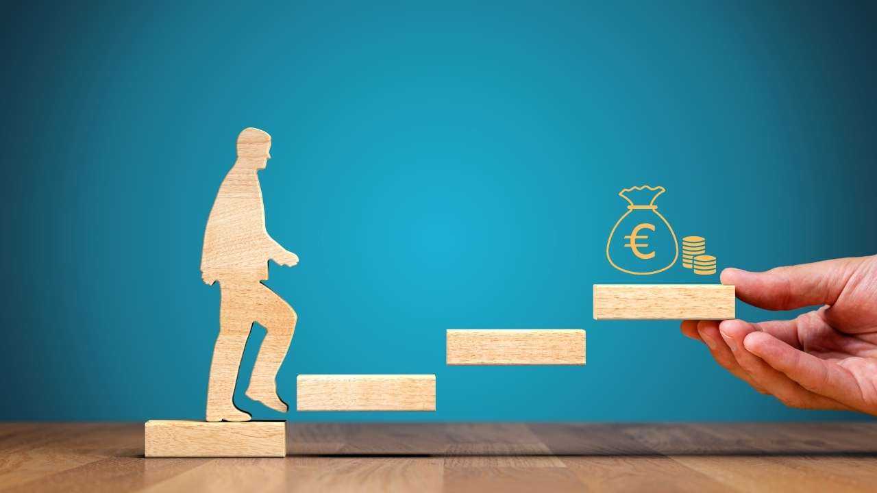 Stilizēts koka cilvēciņš kāpj pa koka kāpnēm, kur augšā gaida maiss ar eiro – nauda strādā kā motivācija