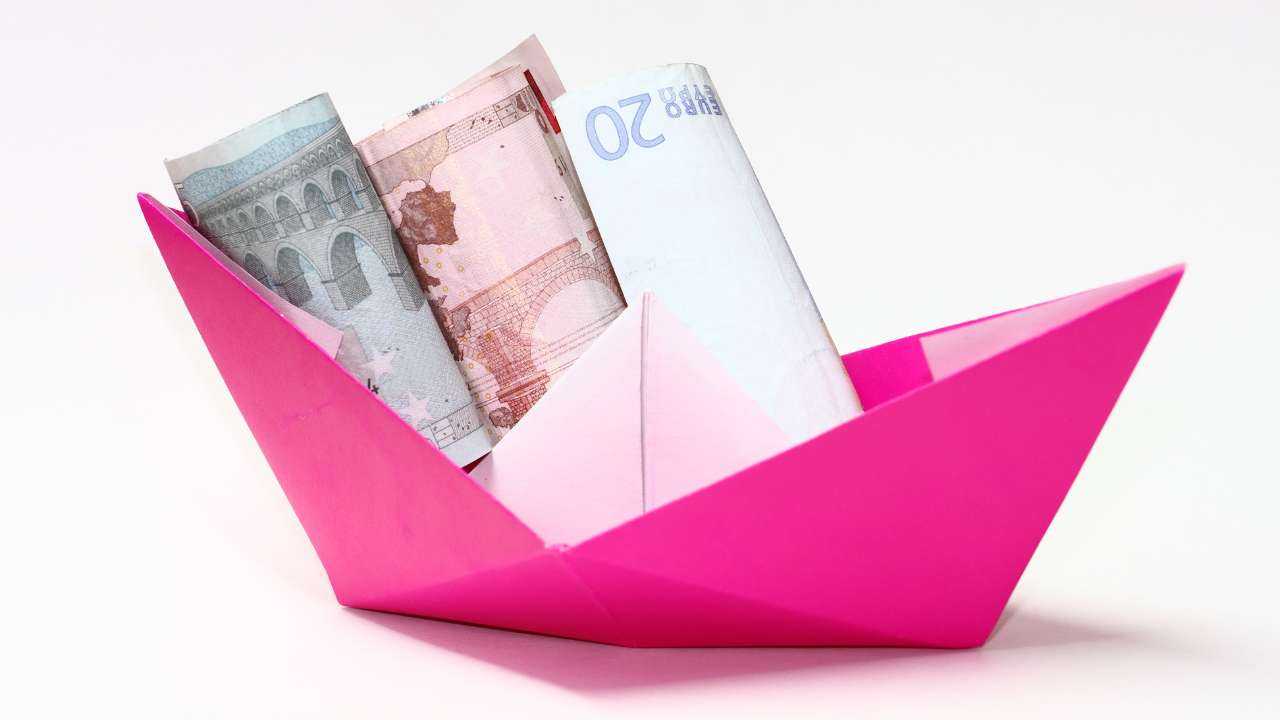 Розовый бумажный кораблик со скрученными в трубочку евро купюрами – деньги в долг можно получить срочно онлайн