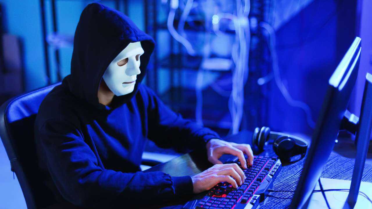 Tumšā telpā finanšu krāpnieks maskā pie datora mēģina apkrāpt cilvēkus, ievācot konfidenciālos datus