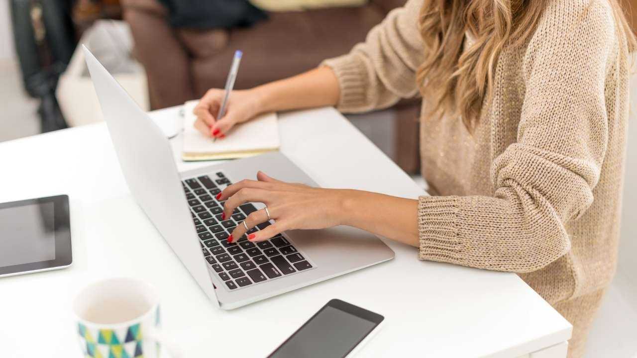 Девушка сидит за ноутбуком и пишет текст, потому что работает фрилансером, что является ее основным заработком в интернете