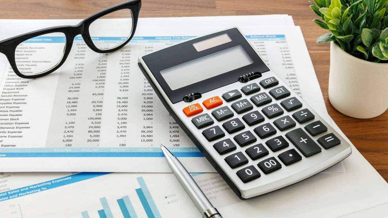 Uz galda nolikts kalkulators un izdevumu pārskats, kas nepieciešams apgrozāmo līdzekļu aprēķināšanai