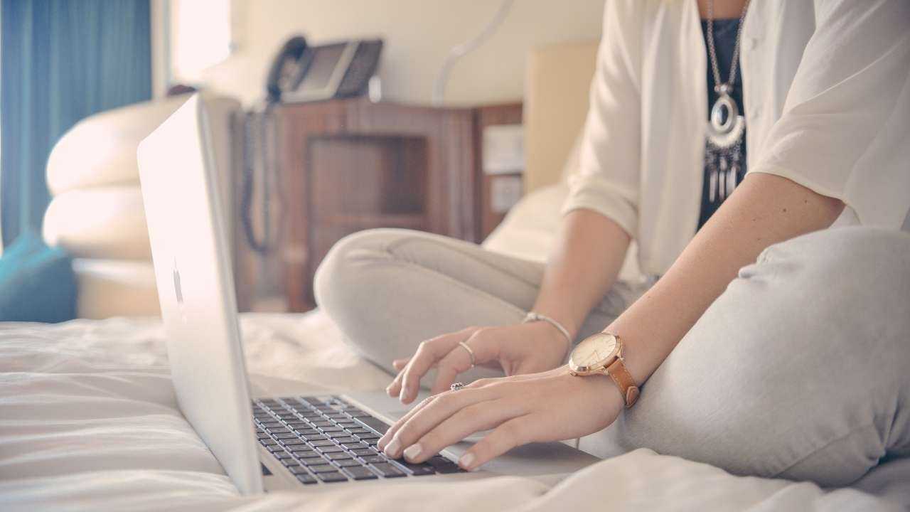 Девушка сидит на кровати и в ноутбуке делает безопасные покупки в интернете