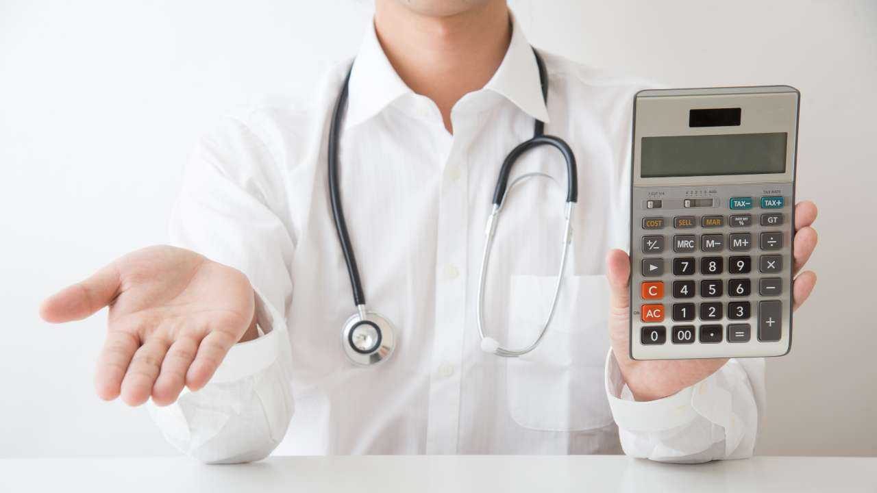 Доктор показывает пациенту калькулятор с ценой за услуги и протягивает руку – узнайте, как экономить на медицинских расходах