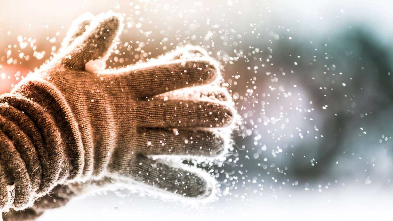 Руки в теплых перчатках под снегопадом как символ финансового гороскопа на февраль 2024