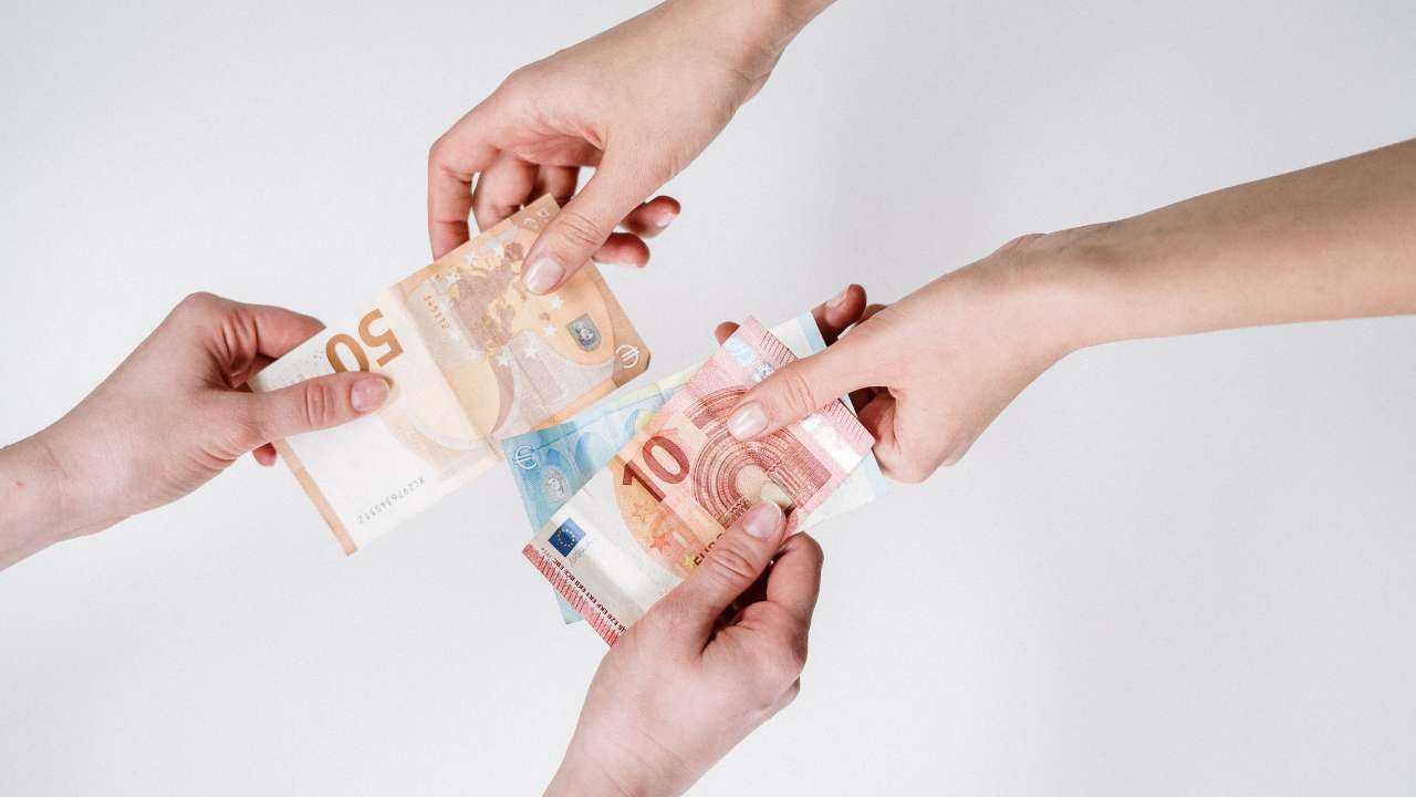 Две пары рук обмениваются евро, иллюстрируя разновидности кредитов, которых в Латвии множество