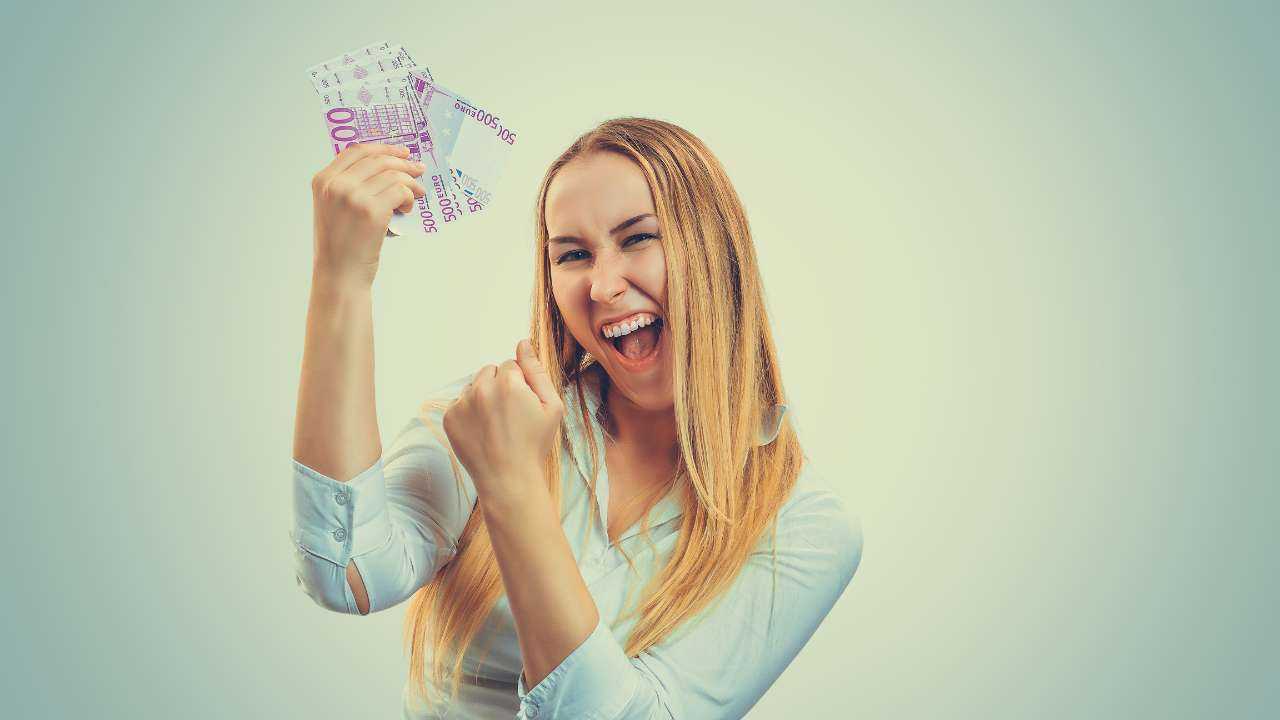 Девушка радостно улыбается, держа в руке веер банкнот из 500 евро, потому что считает, что счастье можно купить за деньги