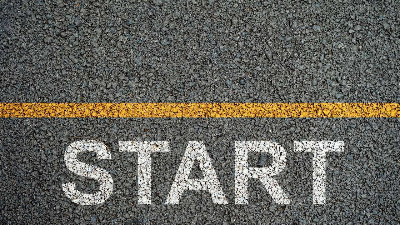 Uz asfalta uzzīmēta dzeltena horizontālā līnija ar vārdu START – laiks uzsākt savu biznesu